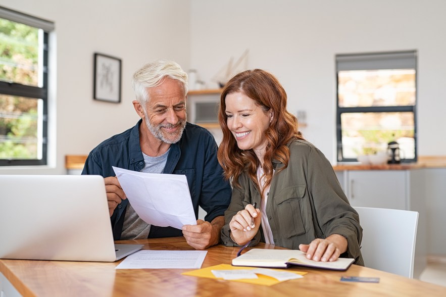 A couple looks over their finances and smiles together.